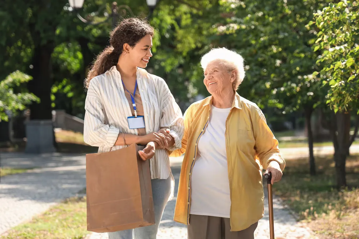 A carer walking outside with an elderly resident