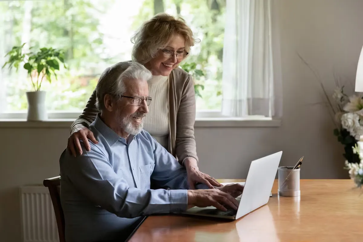 An elderly couple filling in the form together on a laptop