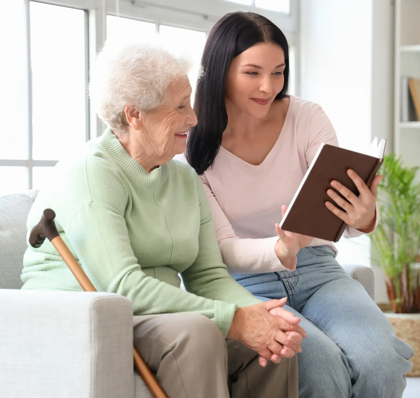 A daughter and her elderly mother laughing together on a sofa